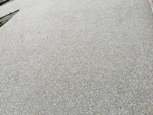 Superficie de hormigón desactivado con pequeñas piedras incrustadas, creando una textura rugosa y antideslizante.
