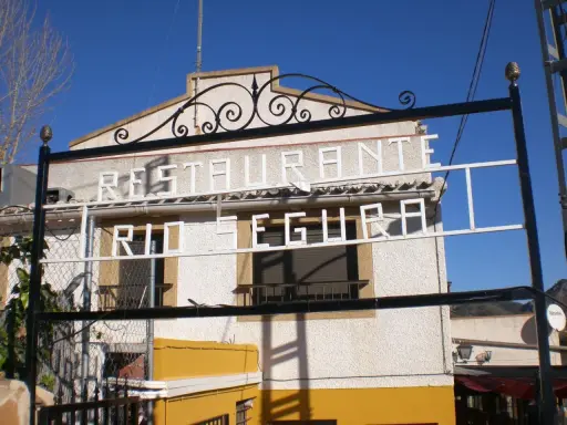 Restaurante El Gallego Elche de la Sierra, con letrero "Restaurante Río Segura" en blanco sobre fachada texturizada.