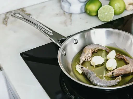 Camarones y ajo en sartén de acero inoxidable, un paso para como curar una sartén de acero inoxidable.