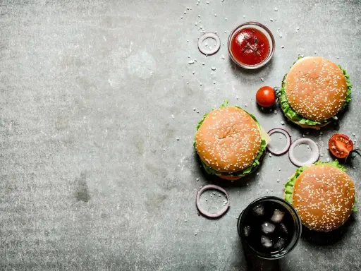 Tre saftiga hamburgare, en skål med ketchup, tomater, rödlök och en läsk med is. Perfekt för en mysig kväll på vår western grillhouse.