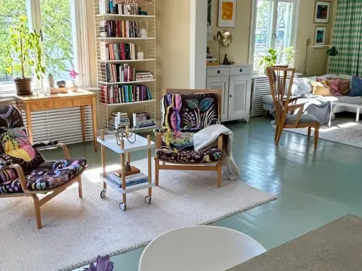 Ljust och luftigt vardagsrum med två färgstarka fåtöljer, bokhyllor och en soffgrupp. En harmonisk känsla som påminner om feng shui vardagsrum.