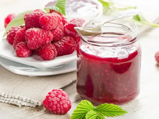Frische Himbeeren und ein Glas selbstgemachte Himbeermarmelade. Ein einfaches Rezept für den Sommer.