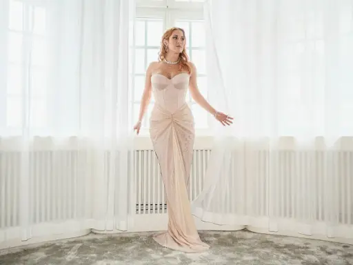 Molly Sandén i en ljusrosa klänning vid ett fönster, redo för Elle-galan.
