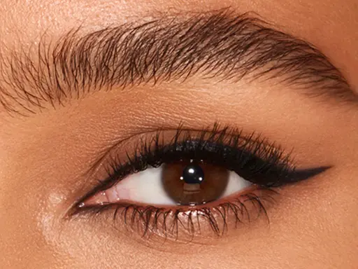 Ojo con pestaña larga y ceja poblada, delineado negro con un sutil eyeliner difuminado en el párpado superior.