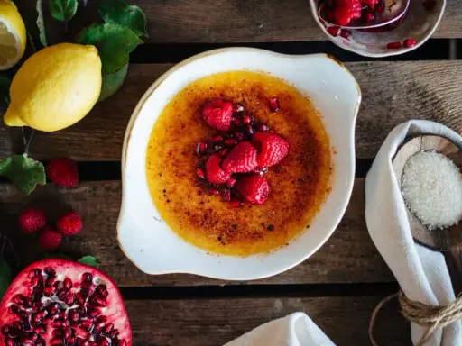 Creme Brulee mit Himbeeren und Granatapfelkernen. Dazu passen Zitronen und Zucker.