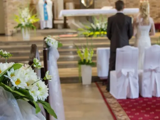 Kwiaty zdobią kościelną nawę. Para młoda stoi przy ołtarzu, przygotowując się do ślubu kościelnego jednostronnego.