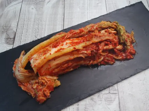 Frisch zubereitetes Kimchi, das beste Kimchi Rezept, liegt auf einem schwarzen Stein.