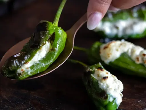 Grön paprika fylld med ost, som pimientos de padron, ligger på en sked.