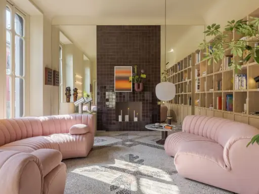 Divani rosa in un luminoso open space con camino moderno e libreria a parete. Case moderne interni open space.