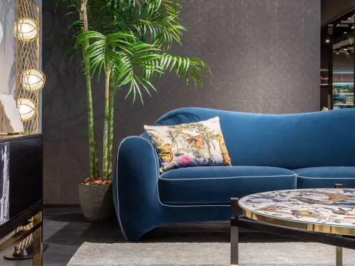 Divano blu petrolio con cuscino decorato. Abbinamenti eleganti con tavolino e arredi moderni.