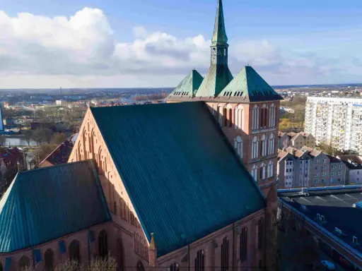 Gotycka katedra z zielonym dachem, otoczona miejską zabudową. Jedna z wielu atrakcji Pomorza Zachodniego.