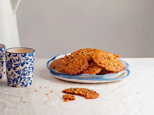 Deliciosas galletas de jengibre con trozos de nuez, servidas en un plato azul y blanco. Perfectas para acompañar un café.