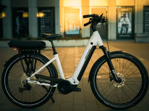Biały rower elektryczny Romet z bagażnikiem i sakwą, gotowy na rower elektryczny duży zasięg.