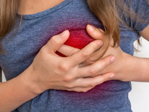 Kobieta trzymająca się za klatkę piersiową, z czerwonym podświetleniem w okolicy serca.