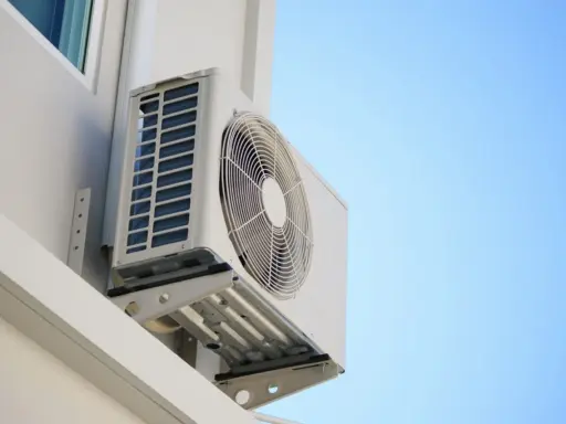 Unidad exterior de aire acondicionado montada en la pared de una terraza cerrada, lista para refrescar el ambiente.