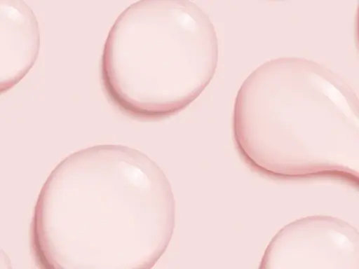 Gocce rosa su sfondo rosa, simili a quelle che si trovano in prodotti con cetearyl alcohol cos'è, un ingrediente emolliente.
