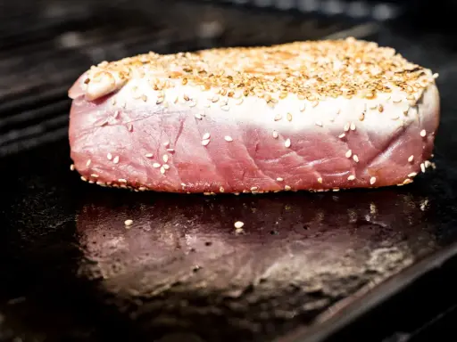 Surowy stek z tuńczyka w sezamie na rozgrzanym grillu.