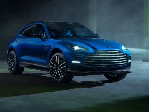 Niebieski Aston Martin DBX 707 lśni w mrocznym, industrialnym otoczeniu.