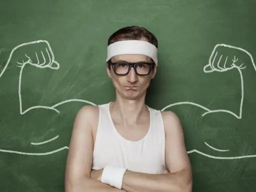 Chudy mężczyzna w okularach i opasce na głowie, z narysowanymi po bokach bicepsami, jakby po zażyciu omnadren 250.