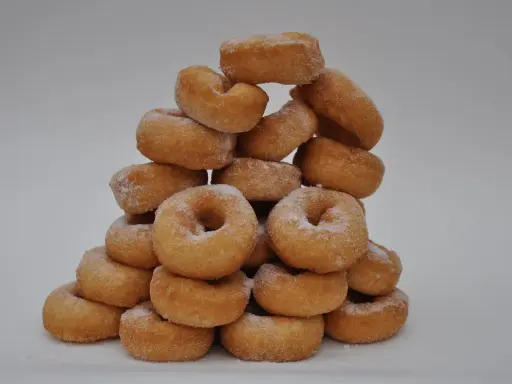 Pile de donuts dorés saupoudrés de sucre, parfaits pour une recette facile de donuts maison.
