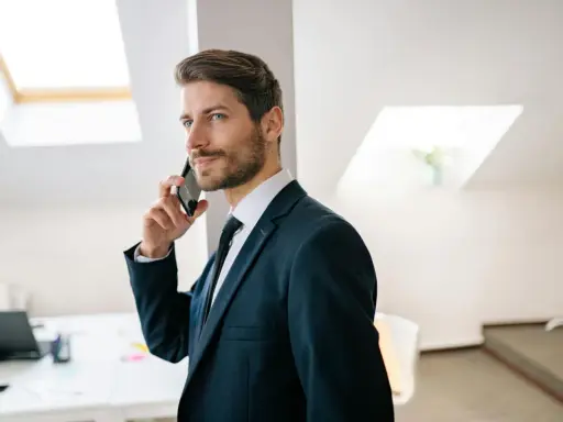 Mężczyzna w garniturze rozmawia przez telefon, jego wyraz twarzy sugeruje, że nastąpiła **zmiana głosu podczas rozmowy**.