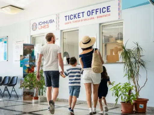 Famiglia in coda all'ufficio biglietti per la Corsica con bambini, pronti per l'avventura.