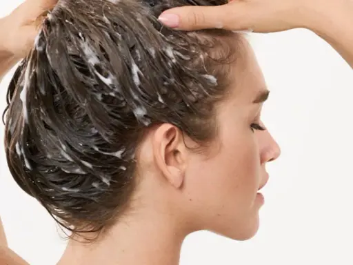 Frau wäscht sich die Haare, Schaum im Haar deutet auf die pflegende panthenol wirkung hin.