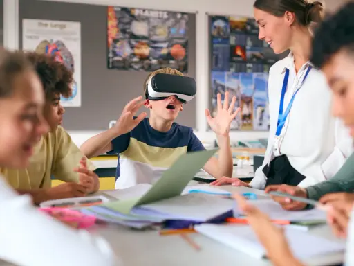 Chłopiec w goglach VR przeżywa lekcję, a nauczycielka z uśmiechem obserwuje tę innowację pedagogiczną.