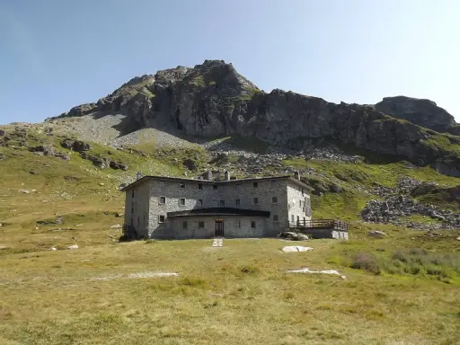 Un imponente rifugio in pietra, incastonato tra prati verdi e rocce imponenti, domina il paesaggio alpino. Un luogo ideale per chi cerca avventura e tranquillità nel cuore della Valle d'Aosta.