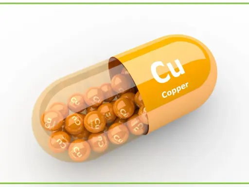 Pomarańczowa kapsułka z wysypującymi się z niej kulkami z napisem "Cu Copper". Suplement diety.