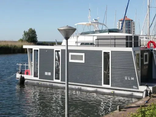 Modernes Hausboot "ULM" im lelystad hafen, umgeben von Schilf und Segelbooten.