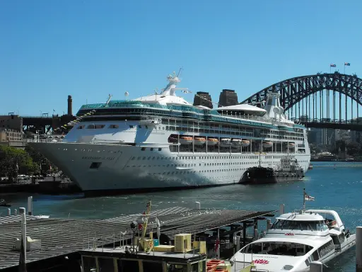 La Rhapsody of the Seas, un'imponente nave da crociera, attracca nel porto di Sydney, con l'iconico ponte sullo sfondo.