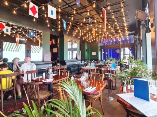 Ambiance marine dans un des restaurants de Saint-Malo. Drapeaux nautiques, lumières tamisées et tables dressées pour un repas convivial.