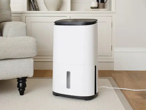 Un deshumidificador blanco moderno junto a un sillón gris, ideal para saber como elegir un deshumidificador y mejorar el ambiente de tu hogar.