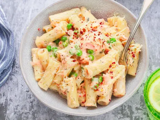 Pyszne danie z makaronem rigatoni, kawałkami łososia, groszkiem i kremowym sosem, posypane serem i płatkami chili. Idealna pasta z łososia na obiad.