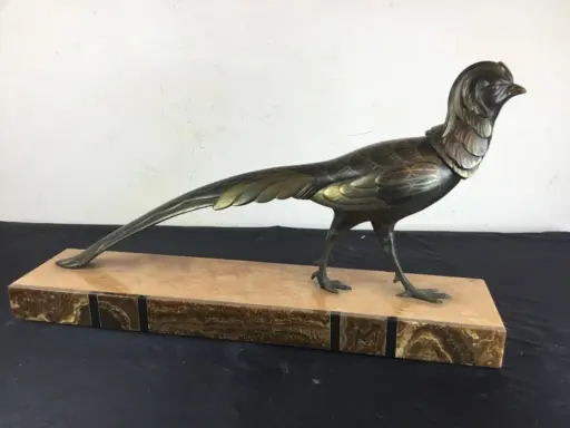 Sculpture d'oiseau en bronze, style Irénée Rochard, sur un socle en marbre veiné. L'oiseau, aux détails fins, arbore une longue queue élégante.