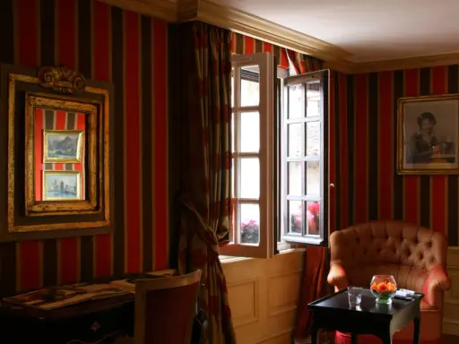 Fenêtre ouverte et miroir pour comment éclaircir une pièce sombre. Un fauteuil confortable et un bureau complètent ce décor.