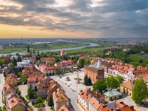 Urokliwy rynek i rzeka w miasto zakochanych w Polsce. Dachy kamienic i zieleń tworzą malowniczy krajobraz.