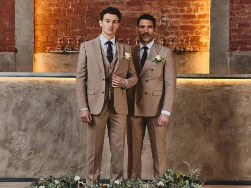 Two men in tan suits stand side-by-side. The man on the left wears a single-breasted suit, while the man on the right wears a double-breasted suit.