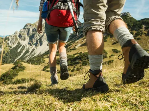 Dobre buty w góry latem to podstawa. Para wędrowców w solidnych trekkingowych butach i skarpetach pokonuje górski szlak.
