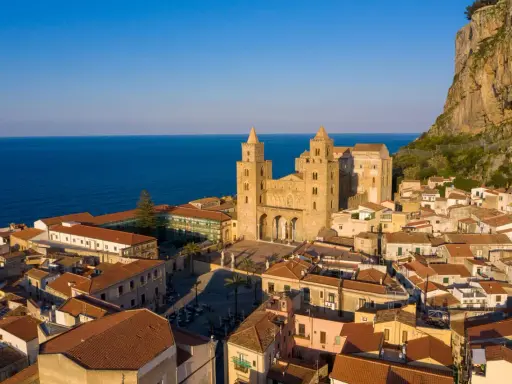 Cefalù cosa vedere: la maestosa Cattedrale Normanna domina il borgo con le sue torri, incastonata tra il mare blu e la rocca imponente.