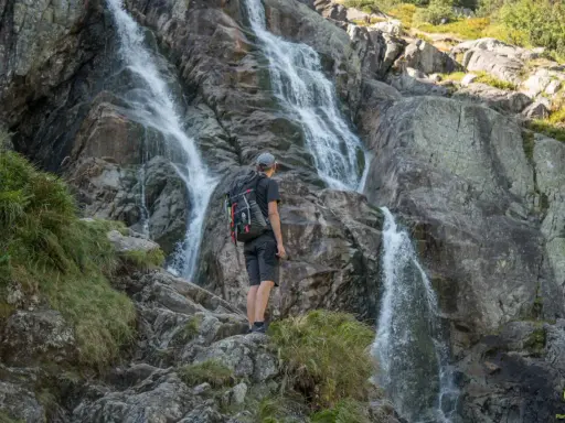 Turysta podziwia wodospad w Tatrach. Wspaniałe widoki, gdzie w Tatry zabierają nas górskie szlaki.
