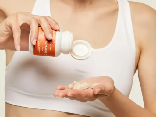 Une main verse des comprimés de vitamine C dans l'autre main, pour une cure revitalisante.
