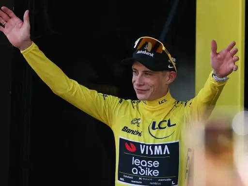 Radfahrer im gelben Trikot der Tour de France winkt jubelnd ins Publikum.