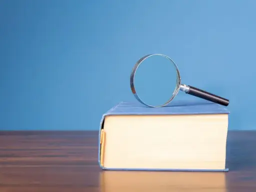 Lente d'ingrandimento su un libro blu, per capire il hic et nunc significato.