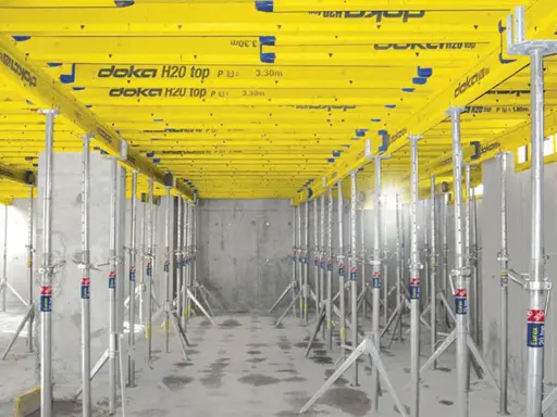 Sistema de apeo estructural Doka H20 top, con puntales metálicos y vigas amarillas, listo para soportar una losa.