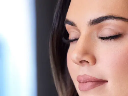 Una mano sostiene un spray fijador de maquillaje rojo. Ideal para cuando usar y mantener tu look perfecto.