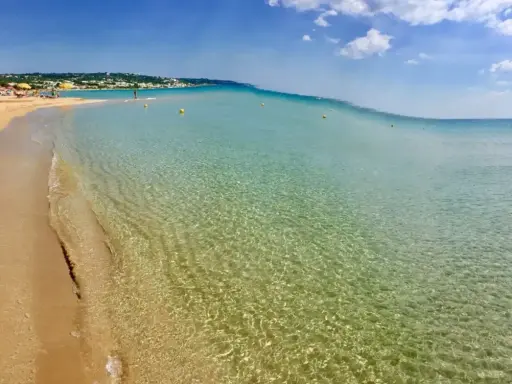 Spiaggia delle Maldive in Puglia: sabbia dorata, acque cristalline e un cielo azzurro con nuvole bianche. Un paradiso terrestre.