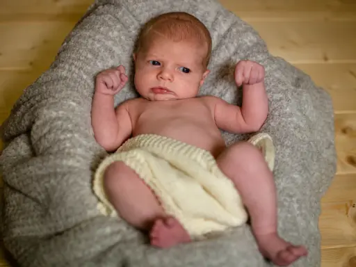 Un neonato con un'espressione curiosa, avvolto in una coperta, pronto per un servizio fotografico flash neonati.