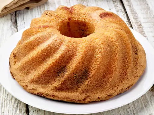 Ciambellone senza uova dorato e soffice, con la sua forma a ciambella, pronto per essere gustato.